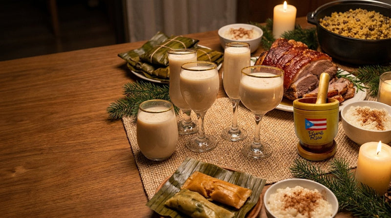 Mesa navideña puertorriqueña con pasteles en hoja, pernil, arroz con dulce, coquito en copas con borde dorado, pilón de madera y placemats dorados