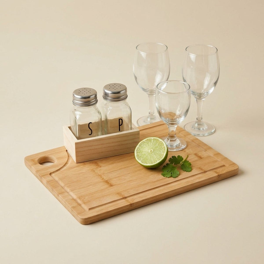 Tabla de bambú, copas de cristal y saleros con bandeja de madera sobre fondo lino
